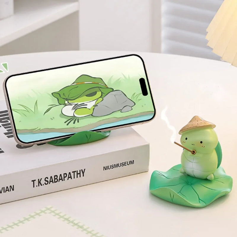 Phone with frog-themed phone holder and figurine on a desk