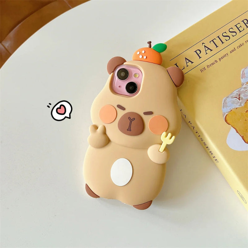 Cute capybara-shaped kawaii phone case on a white surface with a book in the background