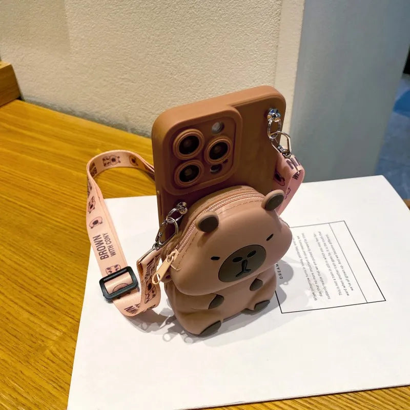 Dark brown capybara-shaped phone case with a matching strap on a wooden surface.