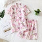 Floral pajama set on a white surface with a plant and book.