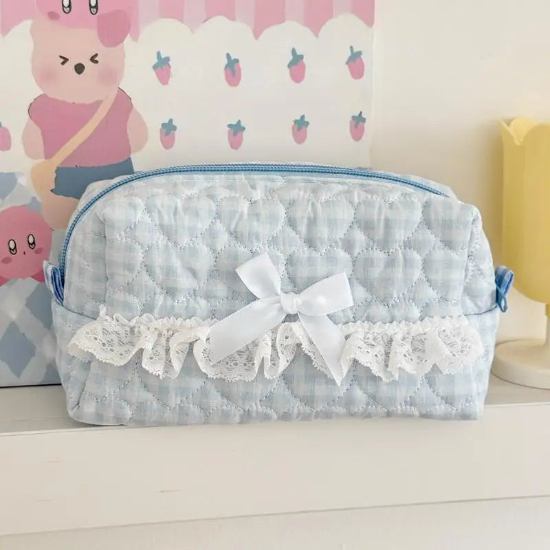 Light blue lace pencil case with a white bow on a white surface, with a colorful background featuring cartoon characters.
