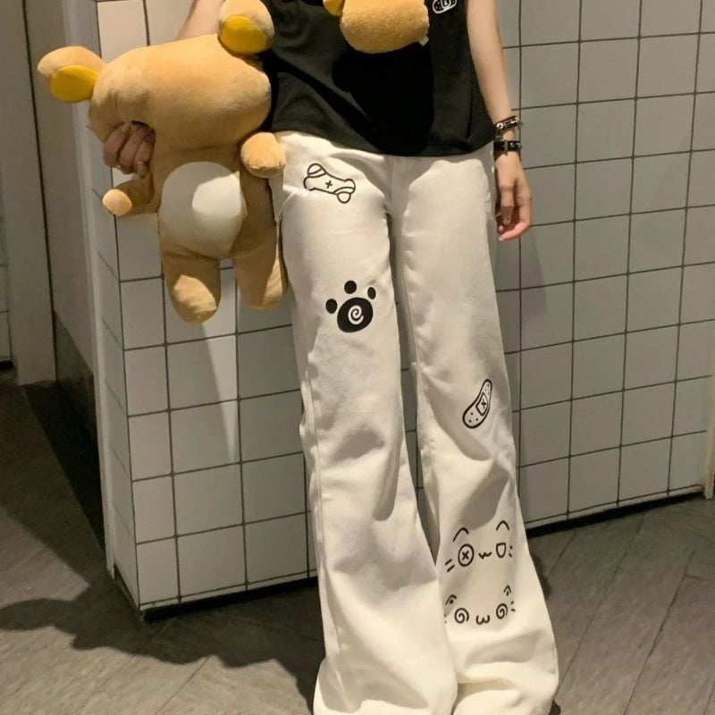Person wearing white pants with paw print designs, holding a plush toy, against a tiled wall.