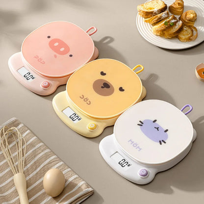 Three kawaii animal-themed electric hot plates on a kitchen counter with food and utensils.