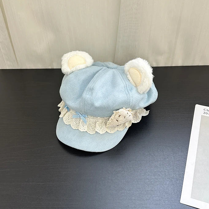 Light blue bear hat with white lace and ears on a dark surface
