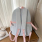 Grey-blue backpack with pink straps on a wooden surface