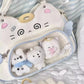 Cute plush toys inside a cat-shaped bag with a face design on a soft background.