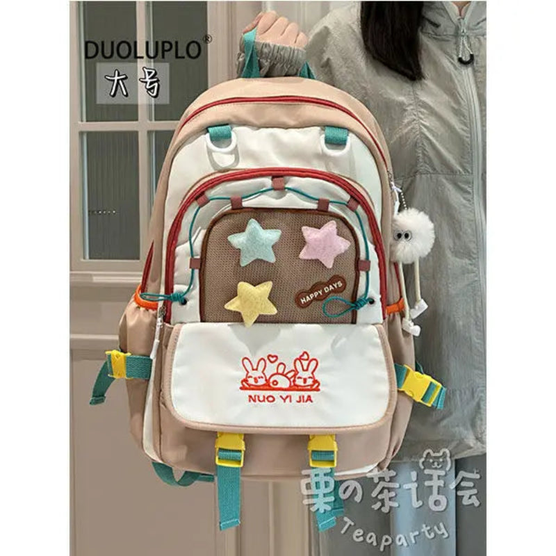 Kawaii backpack with colorful stars and a visible brand logo, held by a person.