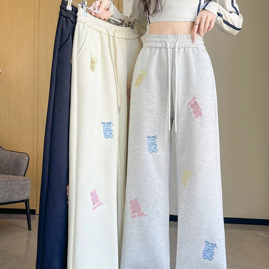 Person holding a pair of embroidered pants with colorful designs.