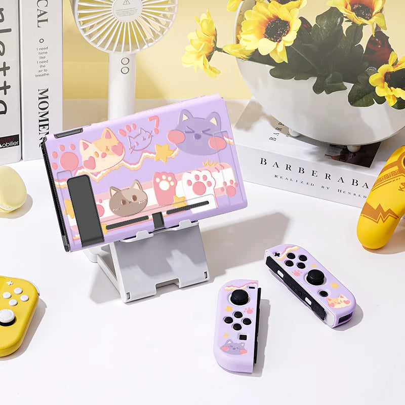Set of gaming controllers with cute designs on a table with a fan and flowers in the background.