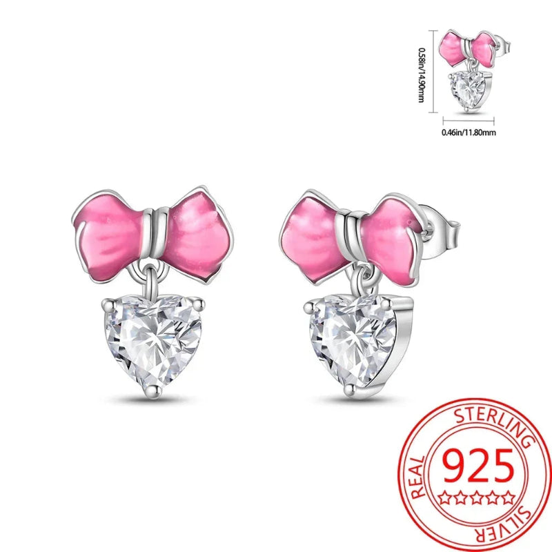 Pink bow and heart-shaped crystal earrings with a 925 sterling silver stamp on a white background.