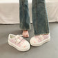 Pink sneakers with Cute cartoon Cat designs worn with blue jeans on a neutral background