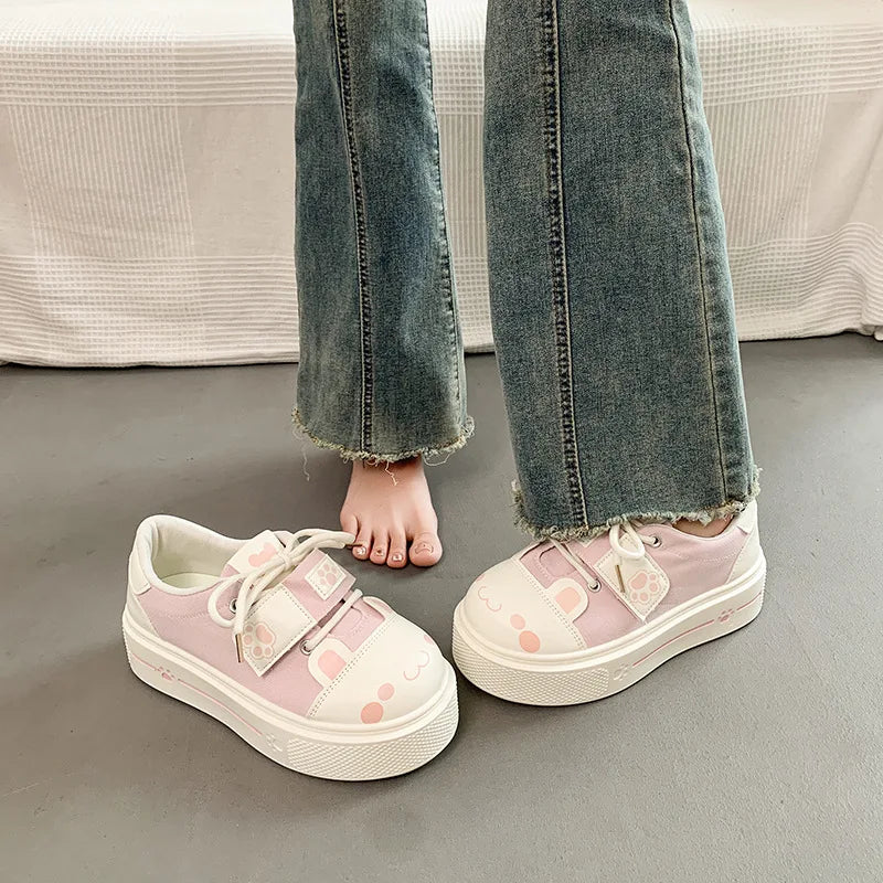 Pink sneakers with Cute cartoon Cat designs worn with blue jeans on a neutral background