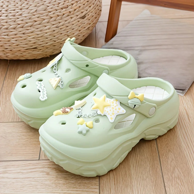 Light green sandals with star and bow decorations on a wooden floor.