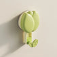 Green wall hook with floral design on a beige wall