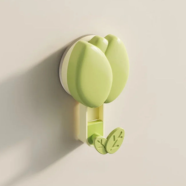 Green wall hook with floral design on a beige wall
