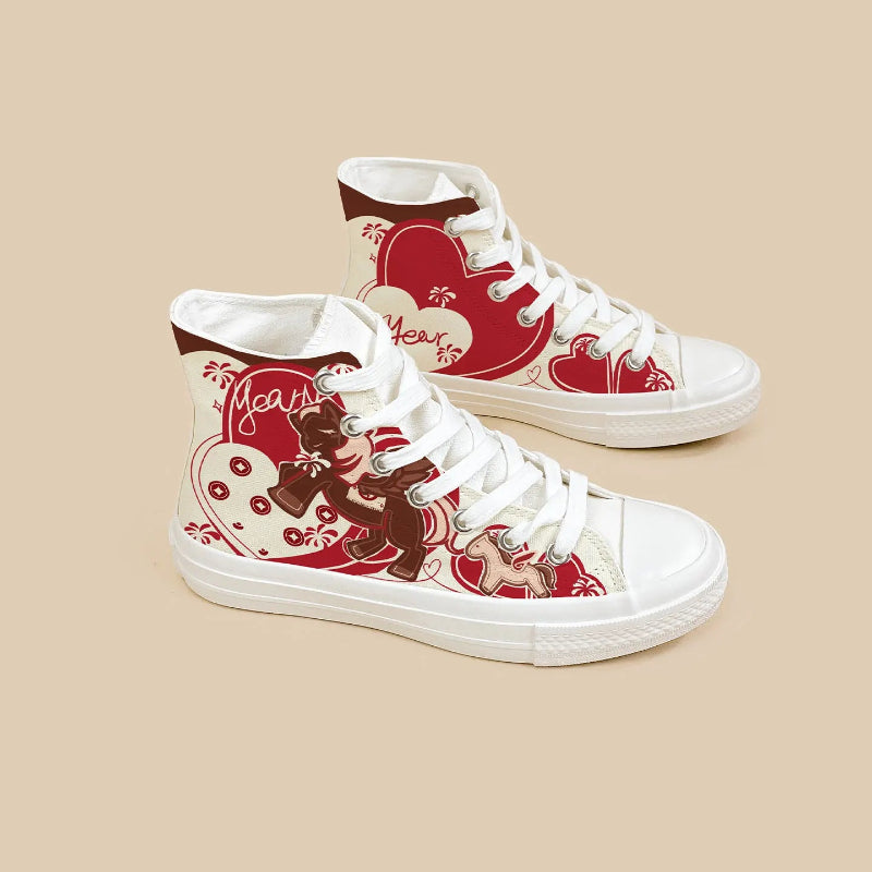 A pair of white high-top canvas sneakers with red and brown graphic prints featuring hearts, swirls, and decorative text, displayed on a solid beige background.