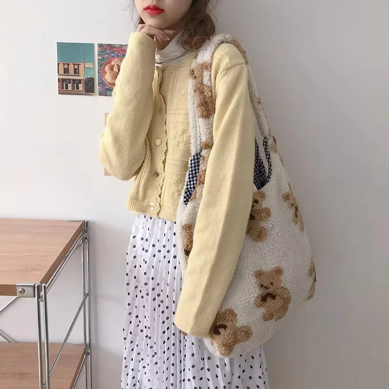 Person holding a teddy bear-patterned bag indoors