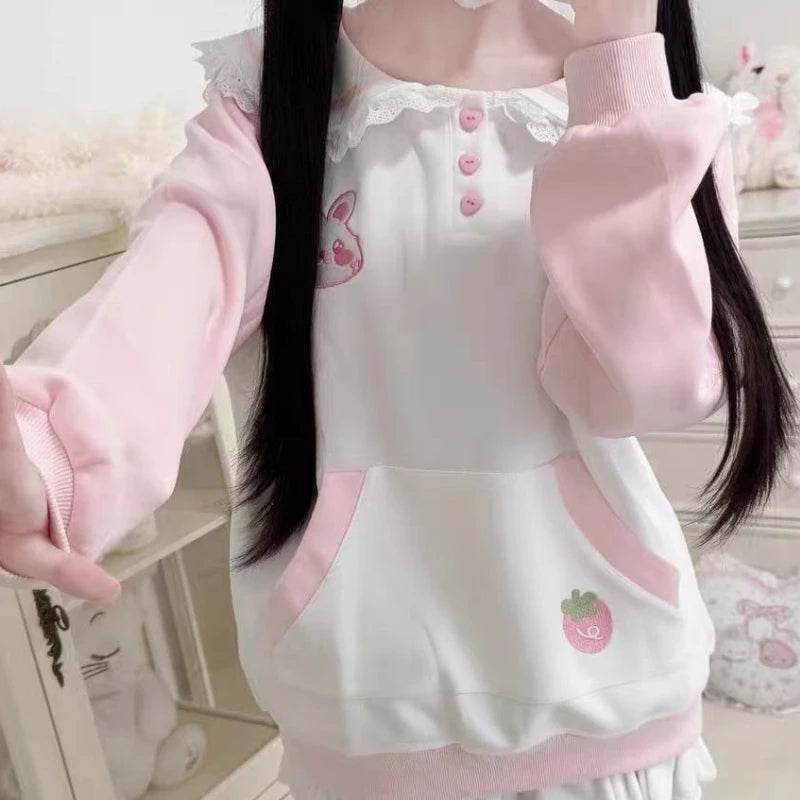 Person wearing a white and pink kawaii  outfit with embroidered designs in a room.