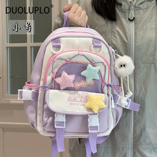 Pastel-colored backpack with star designs held by a person, 