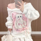 Person wearing a white sweater with a cat design, taking a mirror selfie.