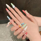 Hand with intricately designed nails featuring various kawaii shapes and colors.