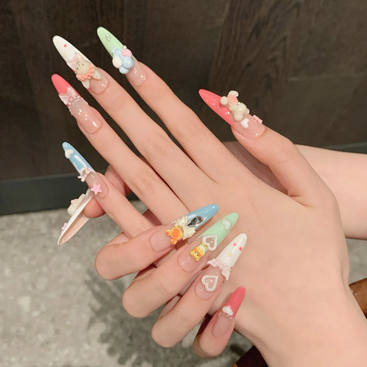 Hand with intricately designed nails featuring various kawaii shapes and colors.