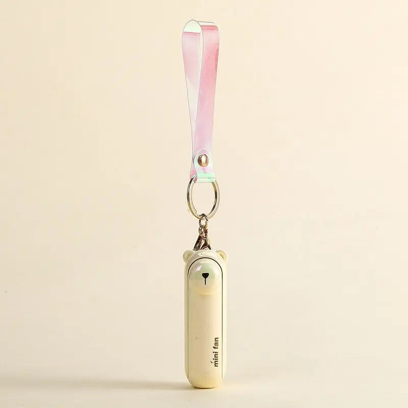 Small handheld bear fan with a keychain on a beige background