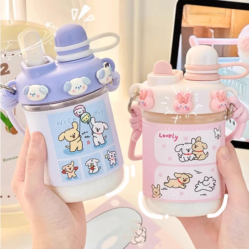 Two cute water bottles with cartoon designs held by hands against a blurred background.