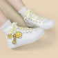 White high-top canvas sneakers with yellow laces and a yellow duck character charm, shown on a model's feet against a light beige background.