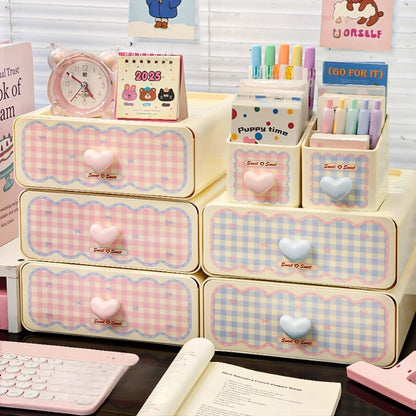 Pink and blue checkered desk organizer with drawers and stationery items on a desk.