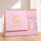 Pink 2026 Desktop Calendar With Sticky Notes on a countertop 