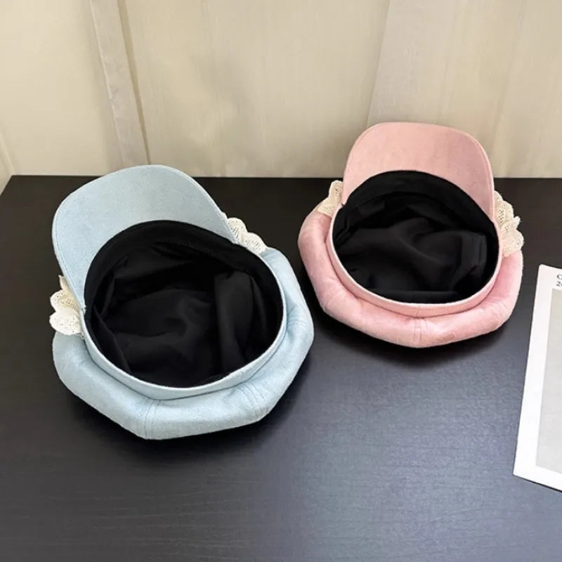 Two hats upside down, one light blue and one pink, on a dark surface with a neutral background.