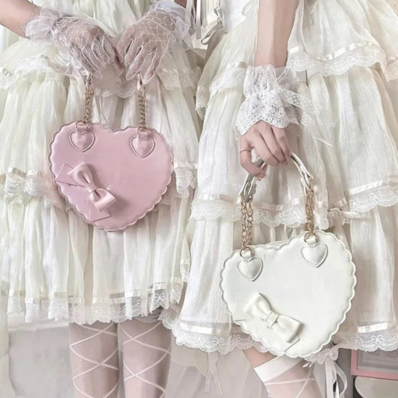 Two people in white dresses holding pink and white heart-shaped bags.