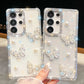 Phone cases with butterfly designs and rhinestones held by a hand. one design is pure white and the other is silver