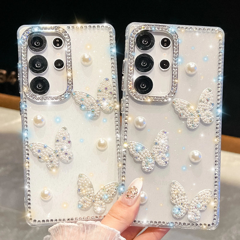 Phone cases with butterfly designs and rhinestones held by a hand. one design is pure white and the other is silver