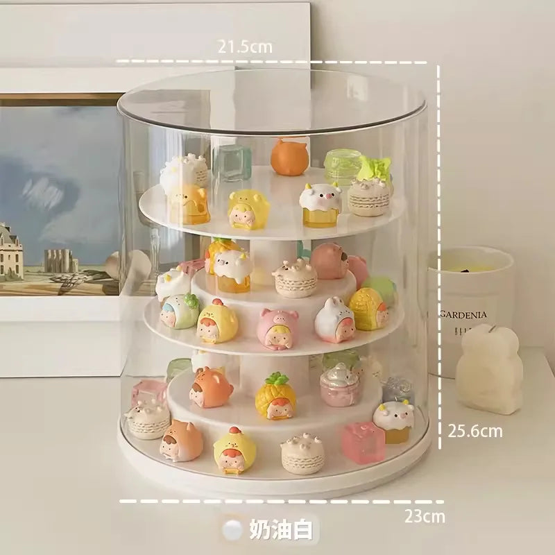 A clear cylindrical rotating display stand with white tiers holding many small pastel novelty items, shown on a tabletop with overlaid dimension labels (21.5 cm, 25.