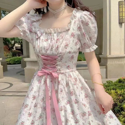 Woman wearing a floral dress with a pink ribbon in an outdoor setting