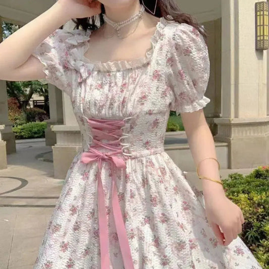 Woman wearing a floral dress with a pink ribbon in an outdoor setting