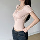 Woman wearing a light pink top and dark jeans against a plain background