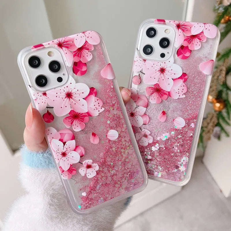 Two phone cases with pink cherry blossom design held by a person.