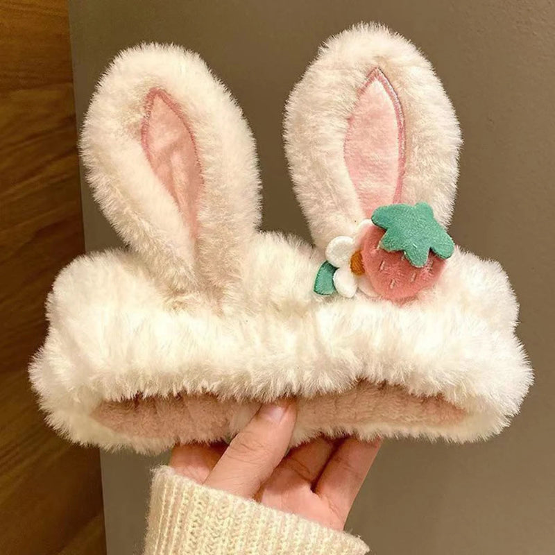 Fluffy kawaii bunny headbands with pink interior and decorative strawberry held by a hand.