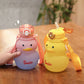 Two cartoon duck-shaped water bottles, one pink and one yellow, on a wooden surface.