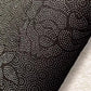 Close-up of black fabric with a subtle pattern on a gray background
