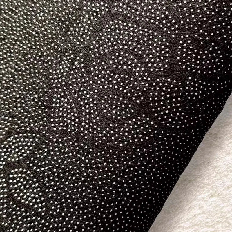 Close-up of black fabric with a subtle pattern on a gray background