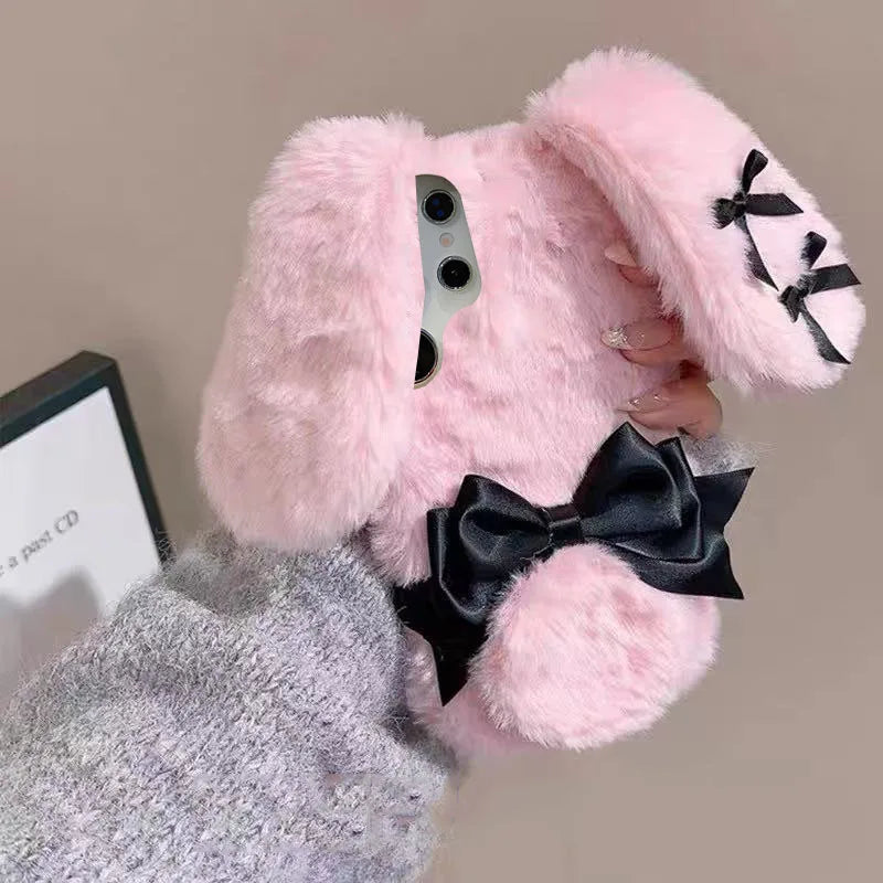 the woman is holding the Kawaii Plush Bunny Samsung Phone Case to display the back of the case , showing off the floppy pink bunny ears.