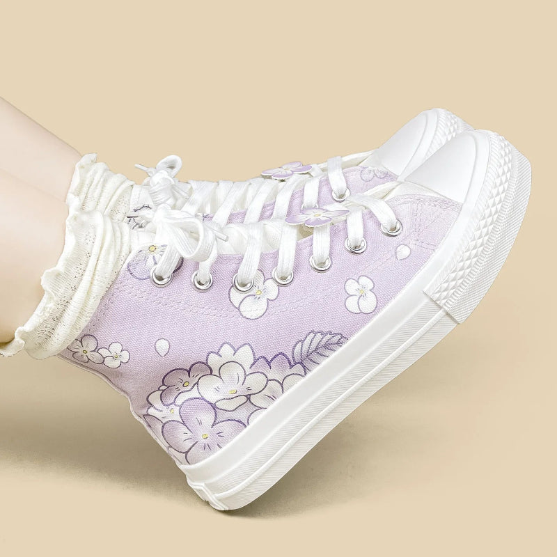 A lavender high-top canvas sneaker with white floral prints, white laces, and a white rubber sole, shown worn with a white ruffled sock against a solid beige background.