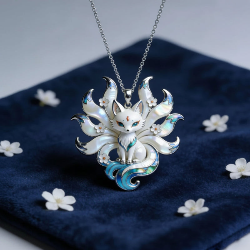 Silver Kitsune pendant necklace on a blue fabric background with white flowers