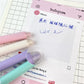 Kawaii Cat Erasable Gel Pens come in purple, pink , turquoise and cream all with different cute cats on them with different faces, this picture is showing the eraser on the pen that can erase the gel pen if you make a mistake, this is shown on a desk background with writing on paper.