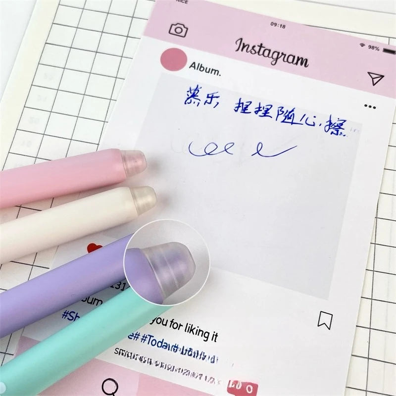Kawaii Cat Erasable Gel Pens come in purple, pink , turquoise and cream all with different cute cats on them with different faces, this picture is showing the eraser on the pen that can erase the gel pen if you make a mistake, this is shown on a desk background with writing on paper.