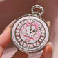 ornate lip balm shaped like a pocket watch held by a hand.